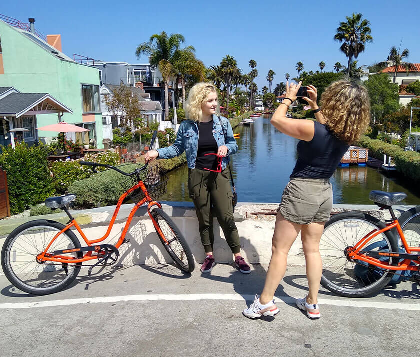 girls taking pictures with bikes on a bridge